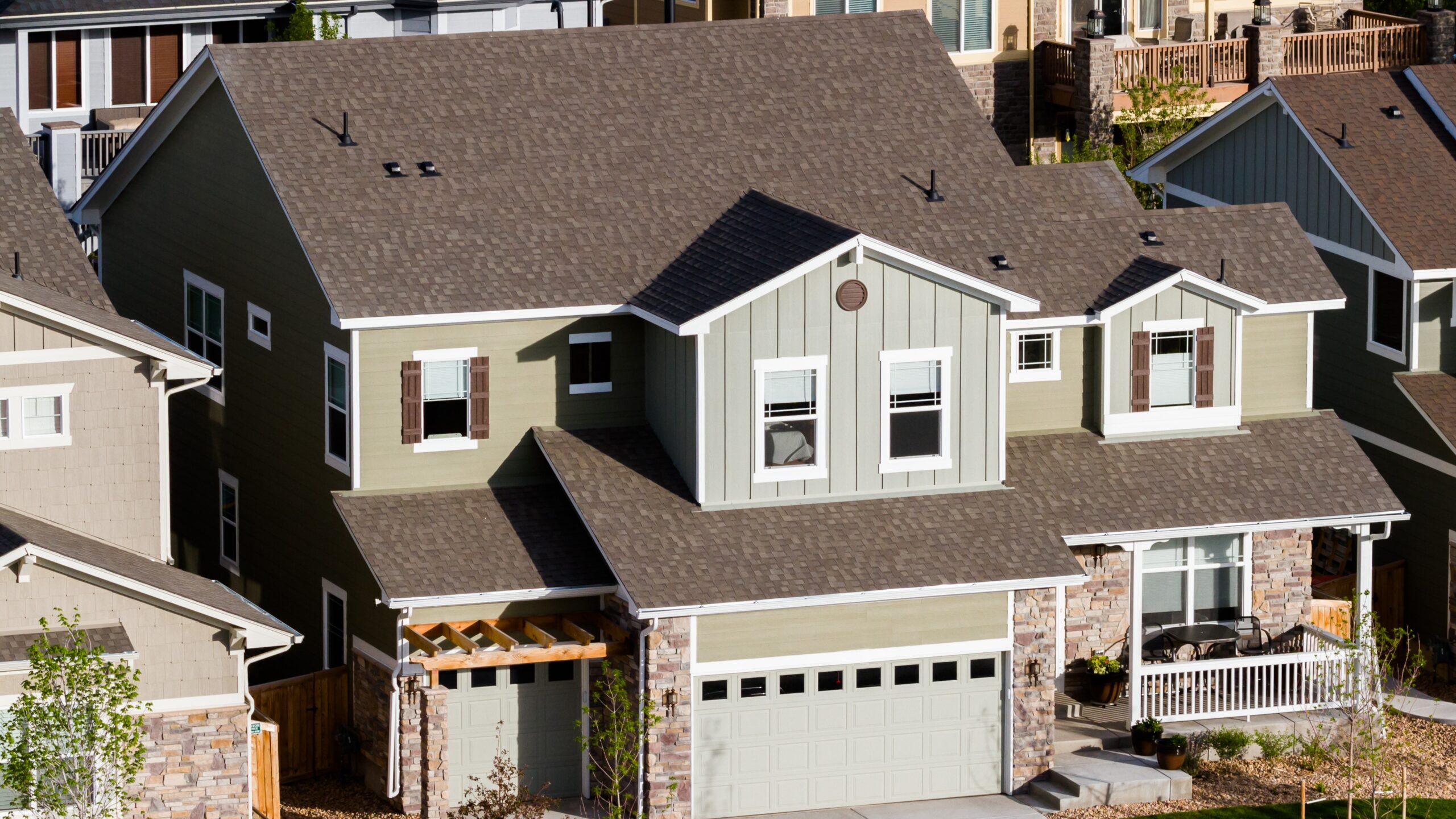 Aerial view of large multi-story home with brown asphalt shingle roofing.