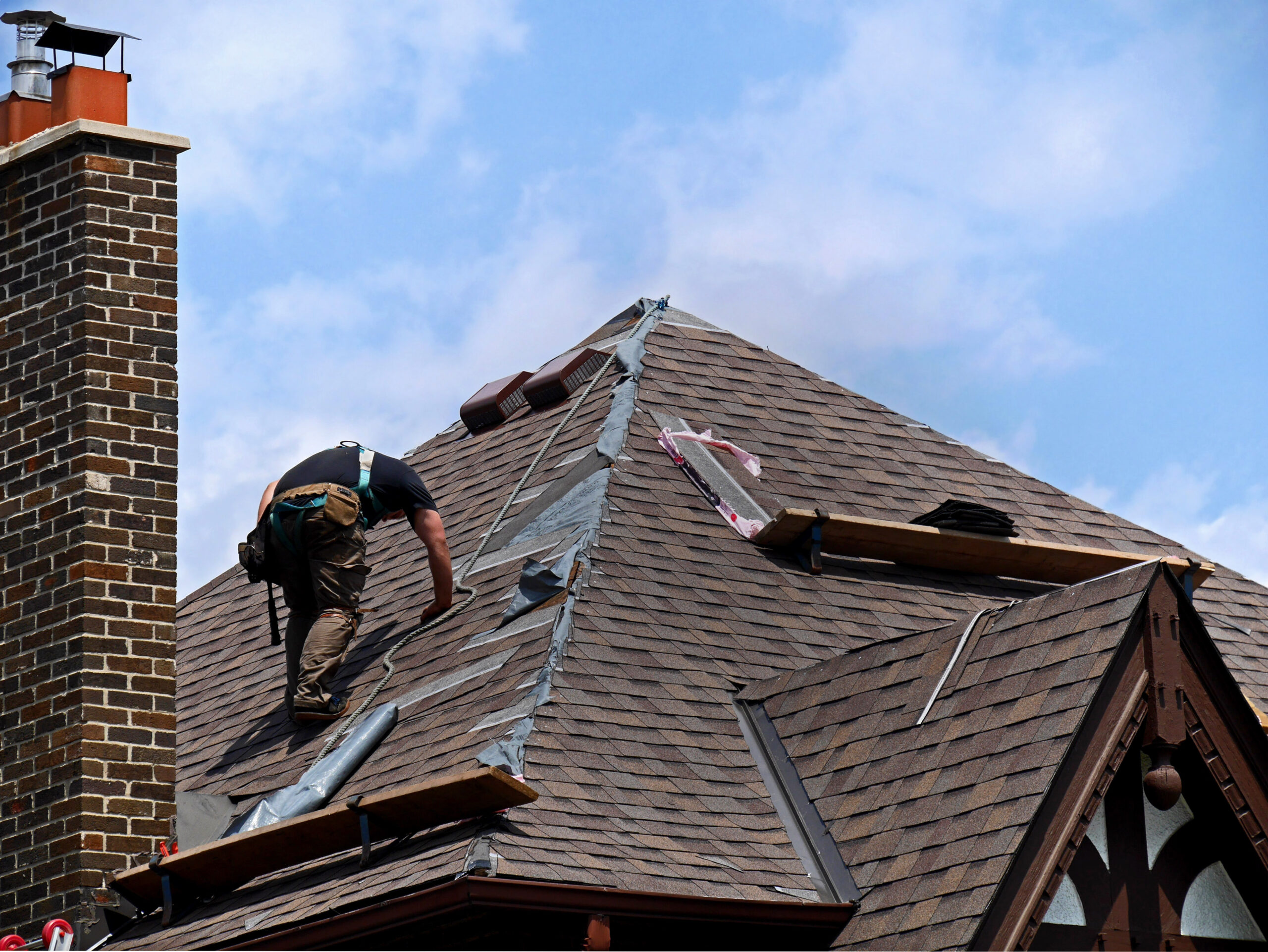 Roofer making repairs on an asphalt shingle roof