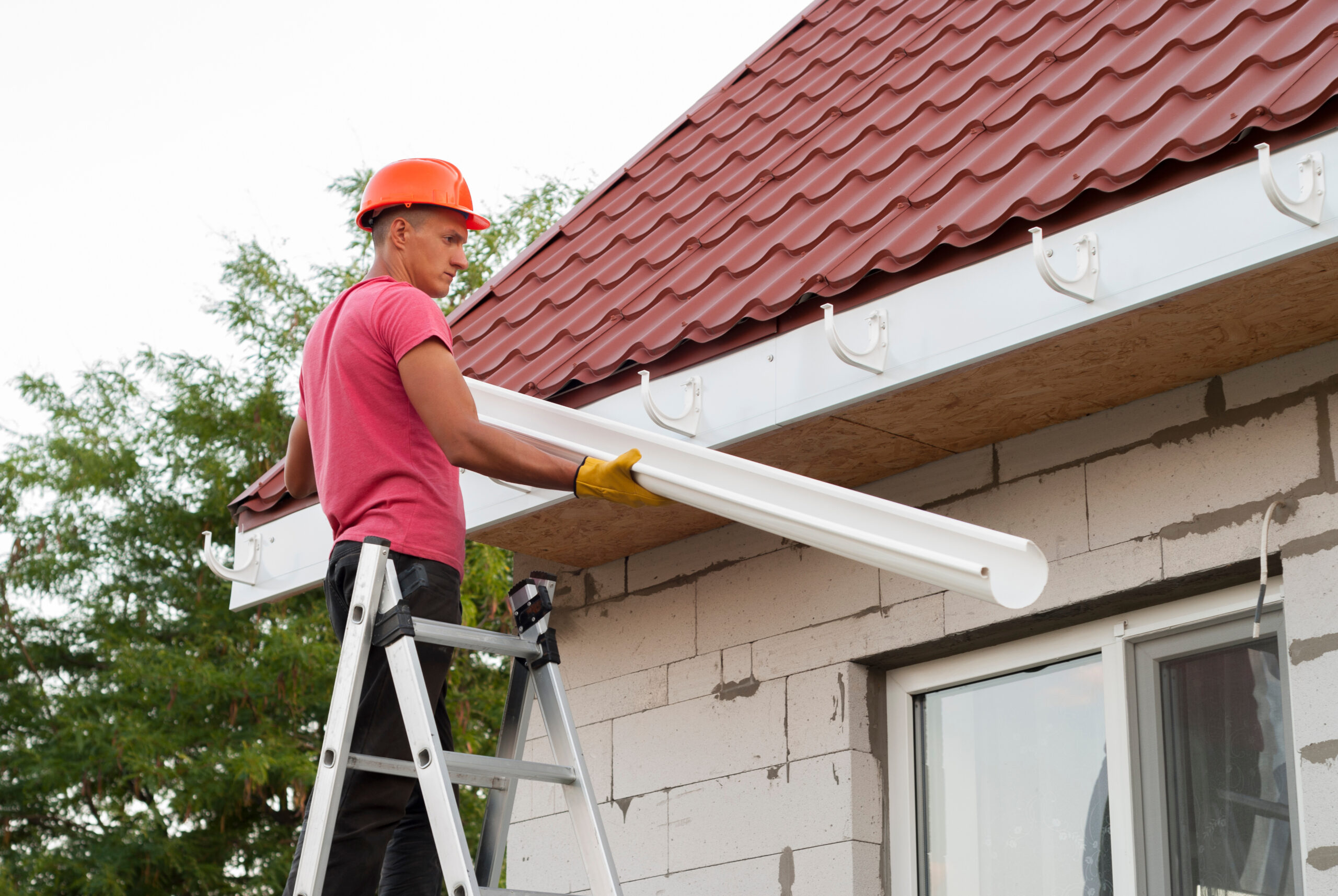 Man installing gutters on a house