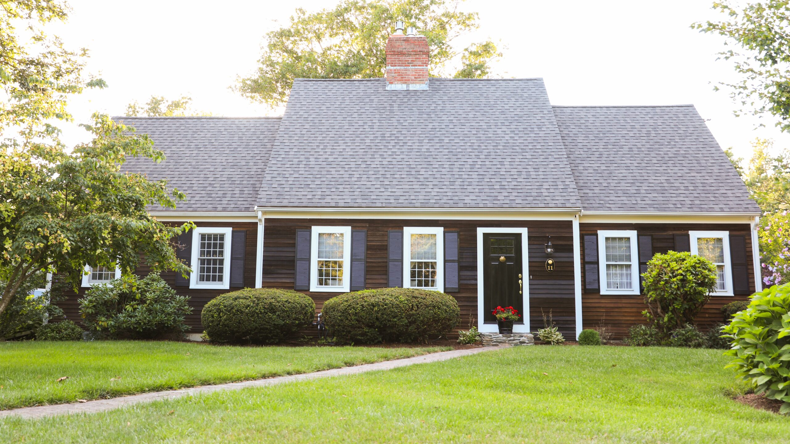 Small home with dark siding and steep-sloped asphalt shingle roof