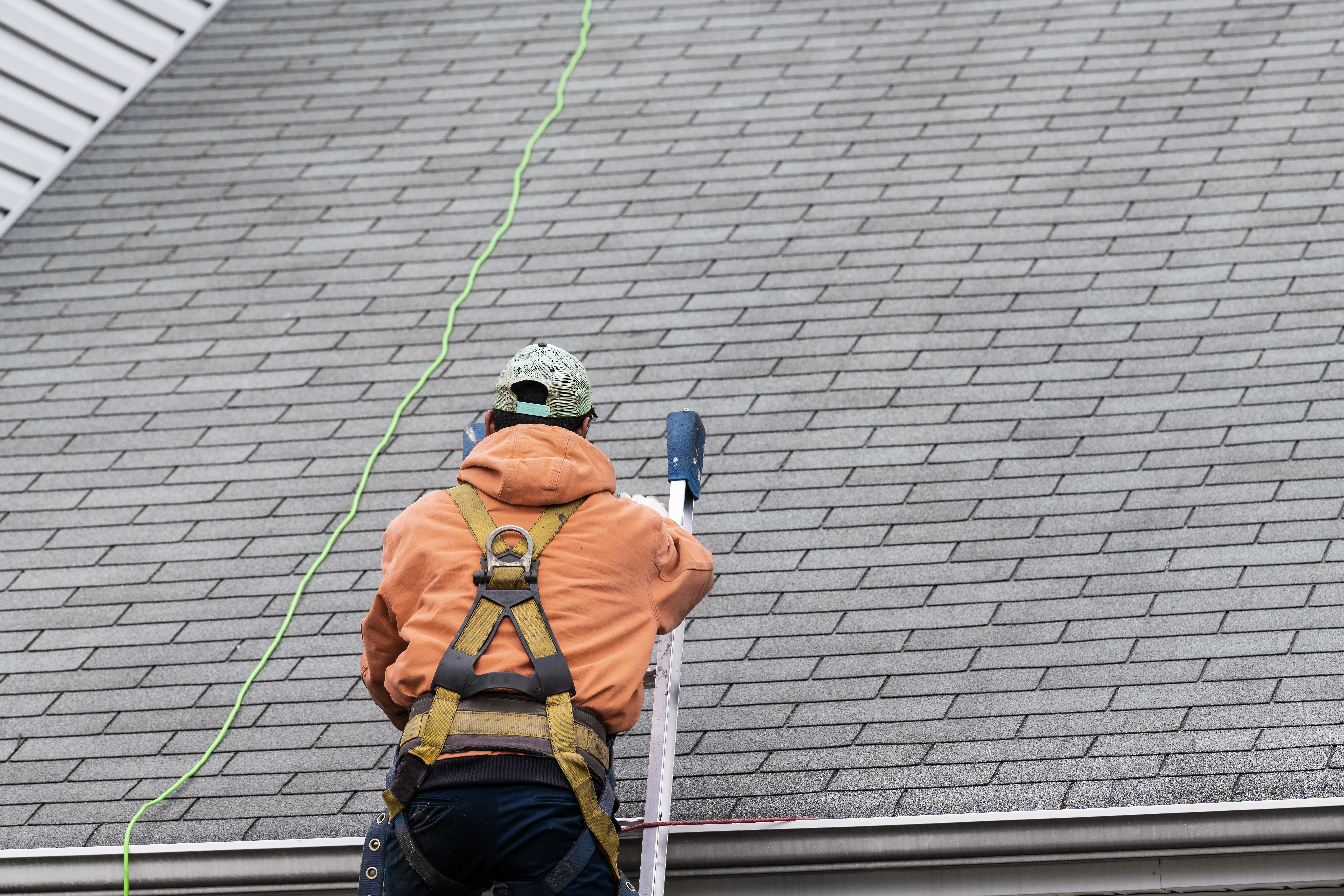 Roofer inspecting an asphalt shingle roof