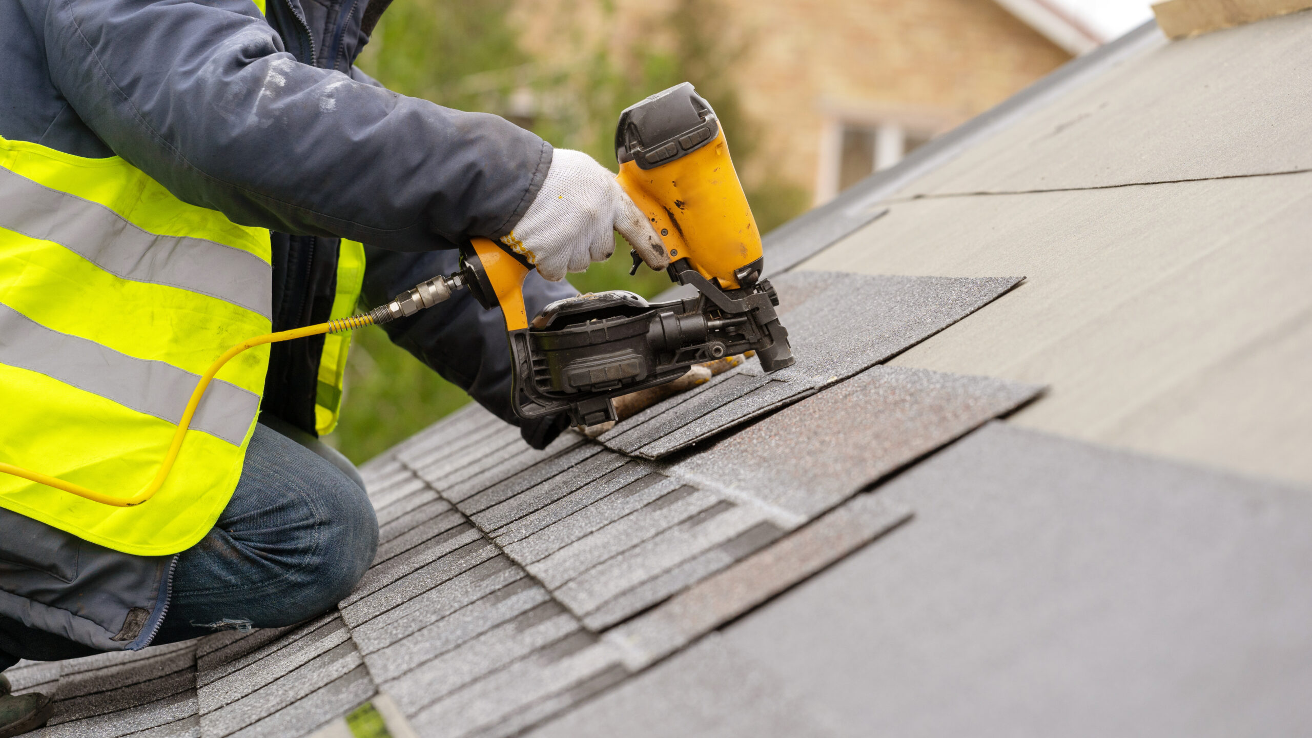 A roofer nailing shingles onto a new roof