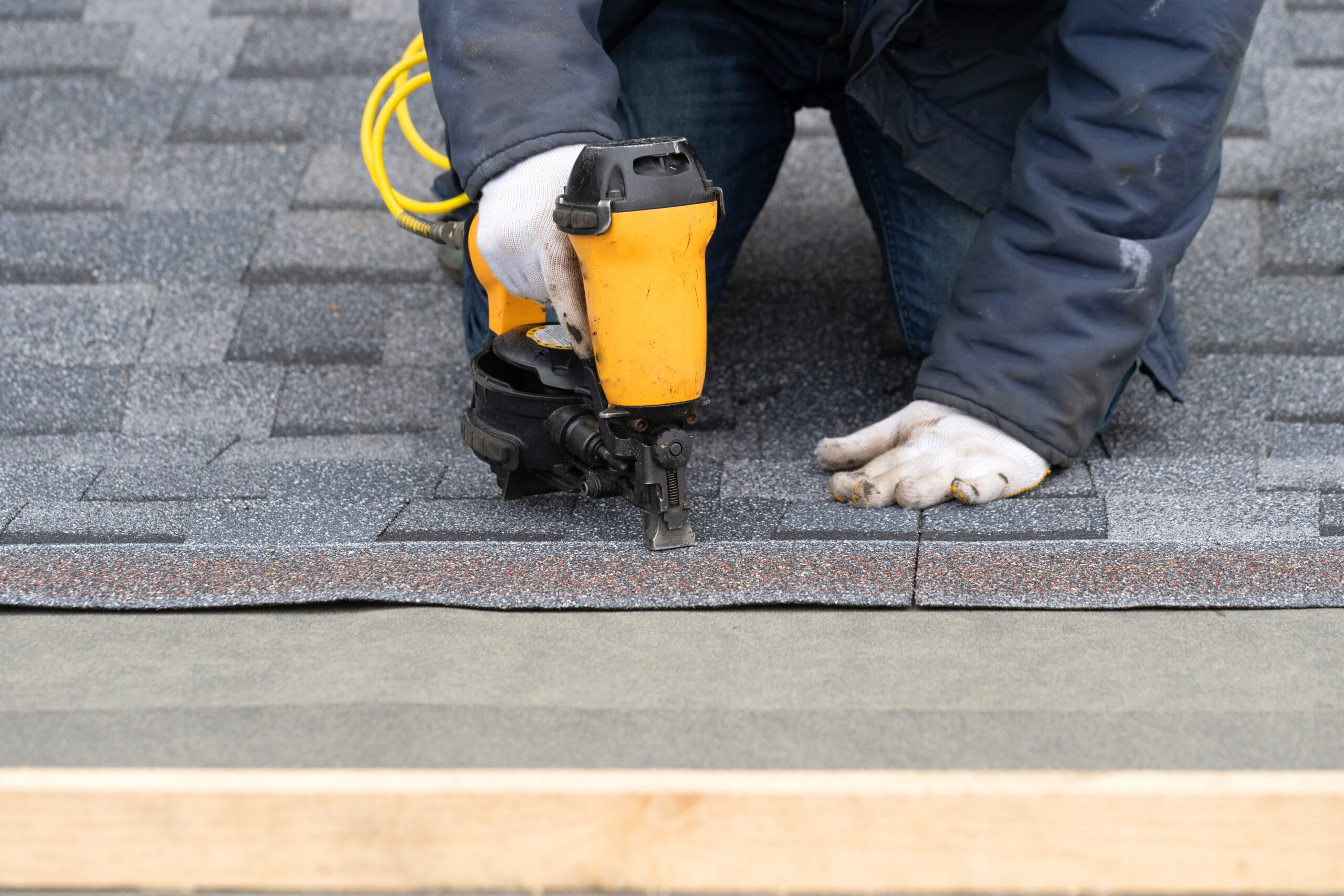 Roofer nailing shingles on a new roof