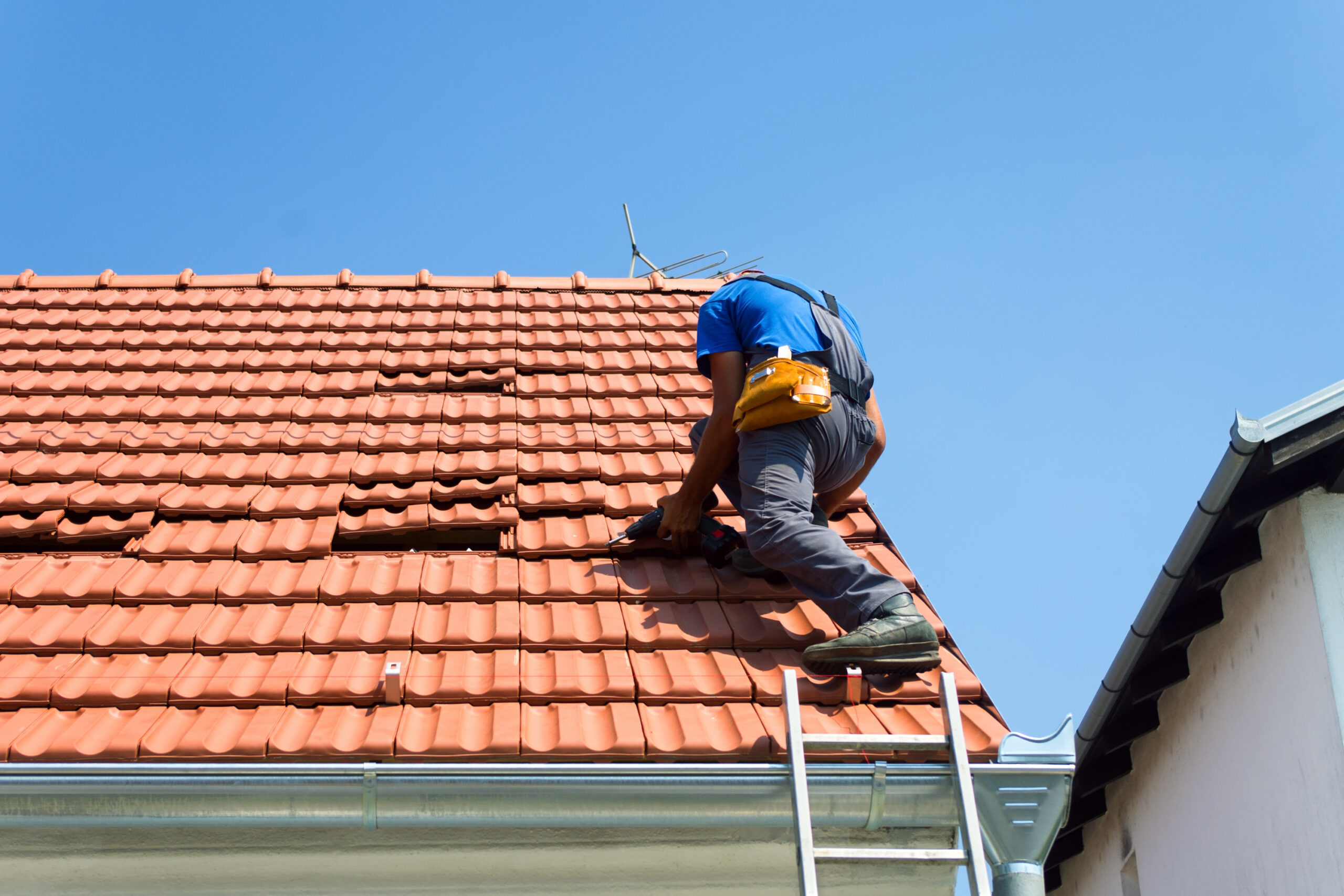 Roofer making repairs to a tile roof