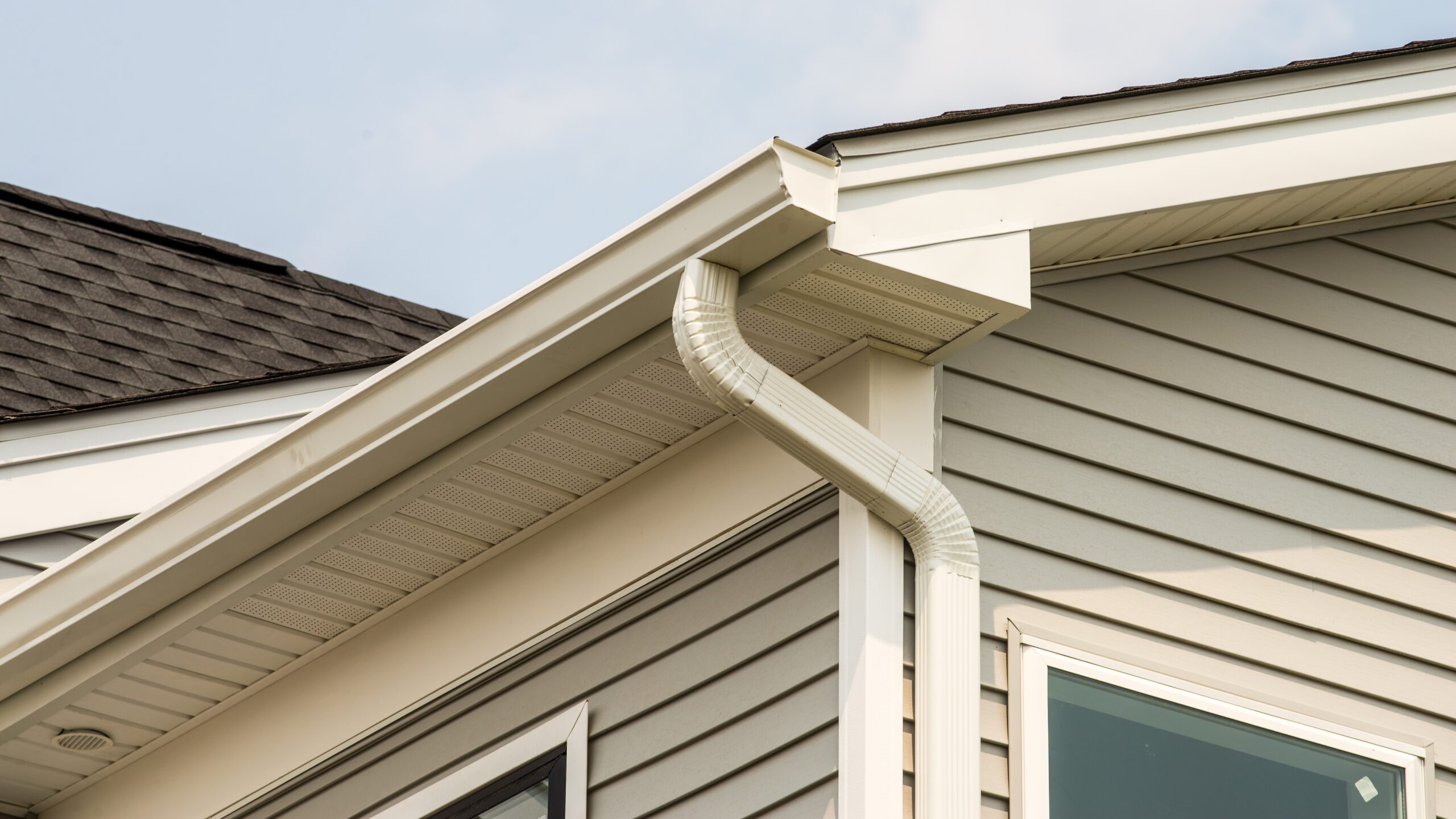 Close-up of newly installed white seamless gutters on home corner