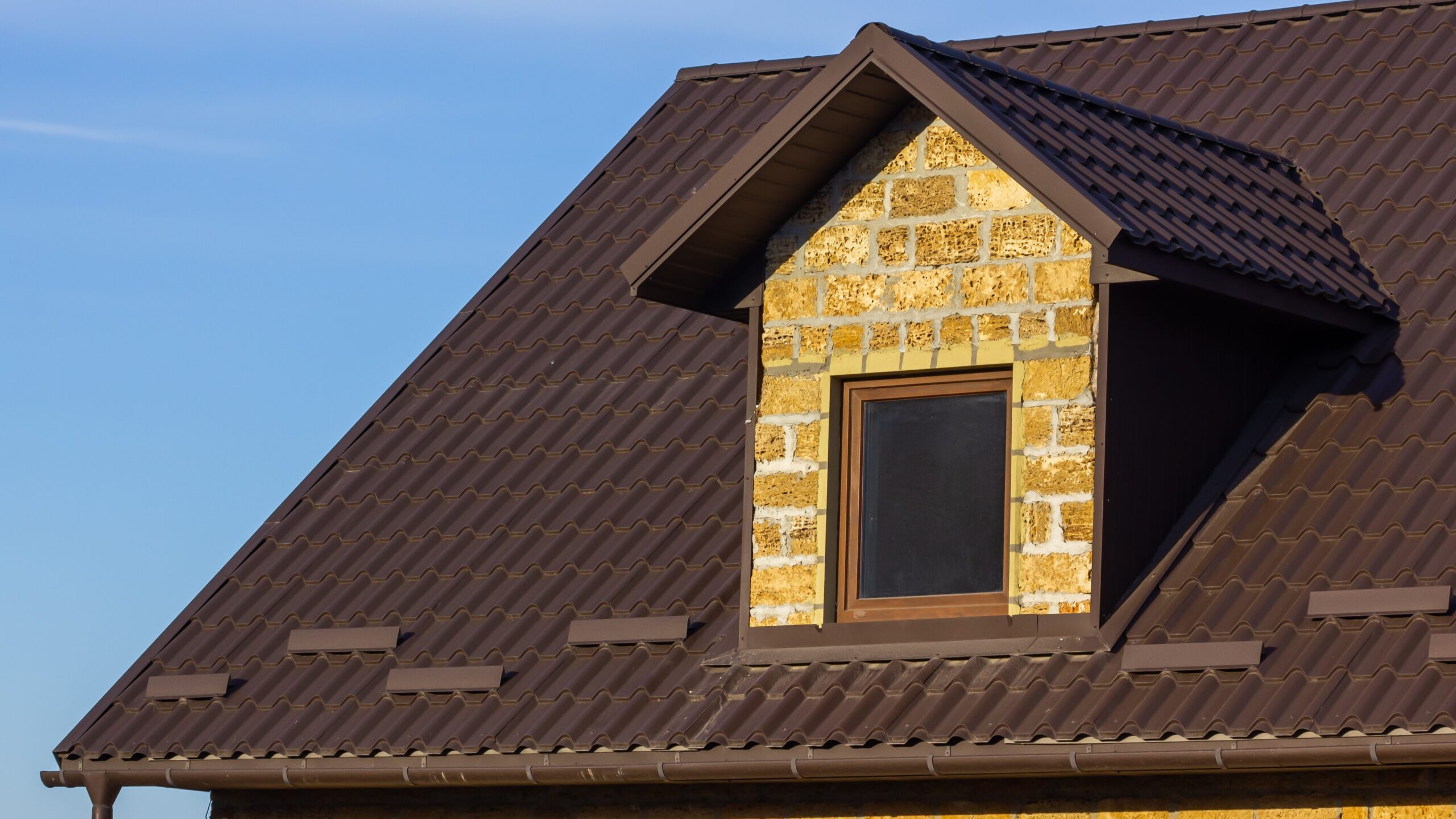 Red metal roof on home with rustic brick siding