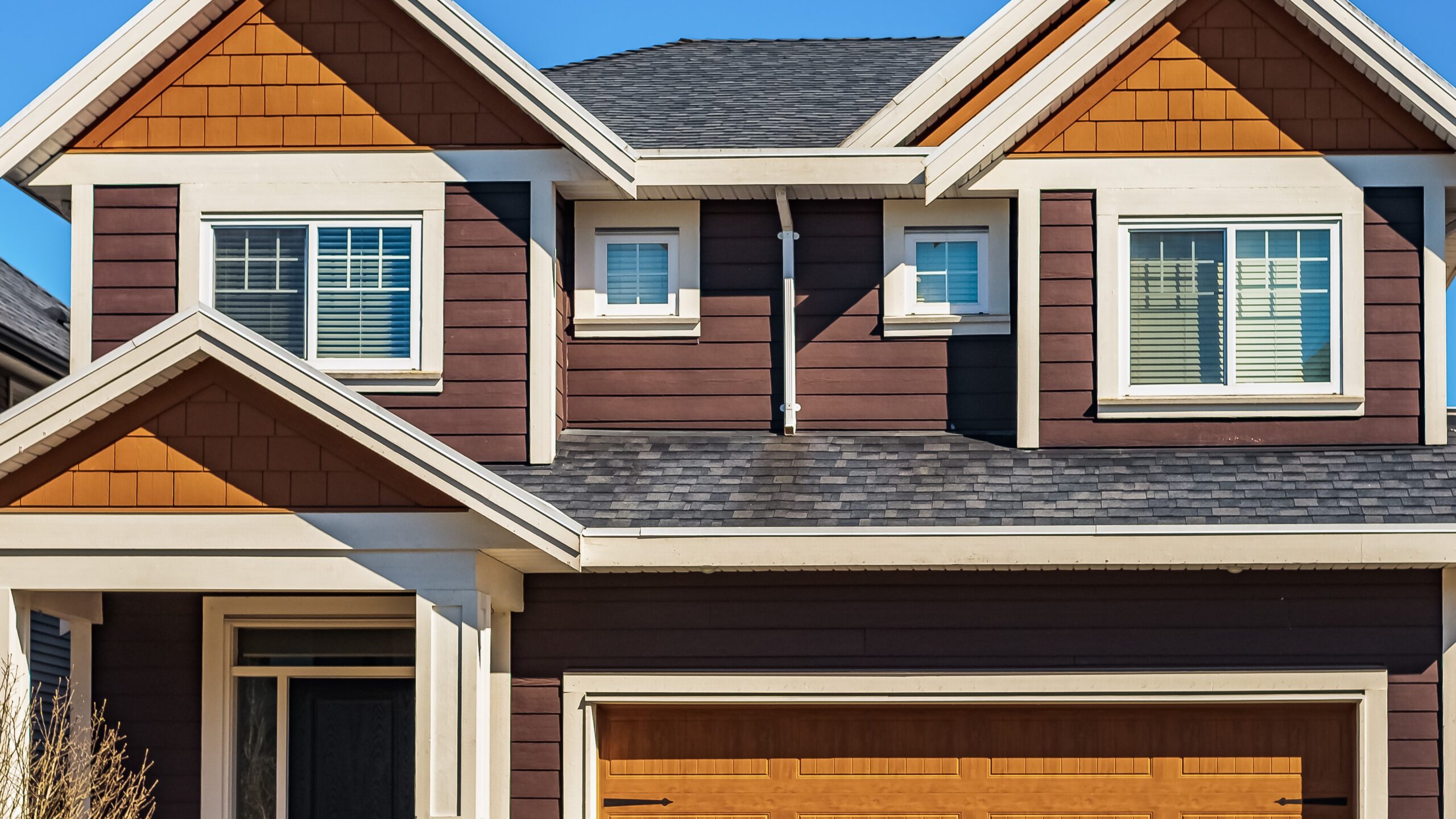 Home with dark wood-colored siding and asphalt shingle roof with beautiful windows