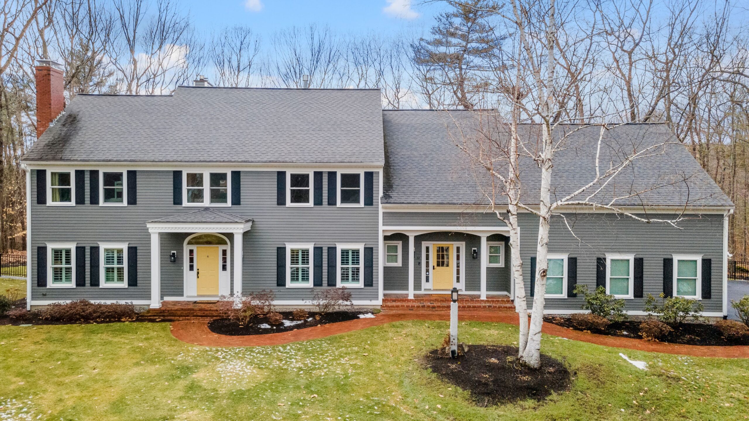 Dark red metal roof on home with a yellow brick facade.