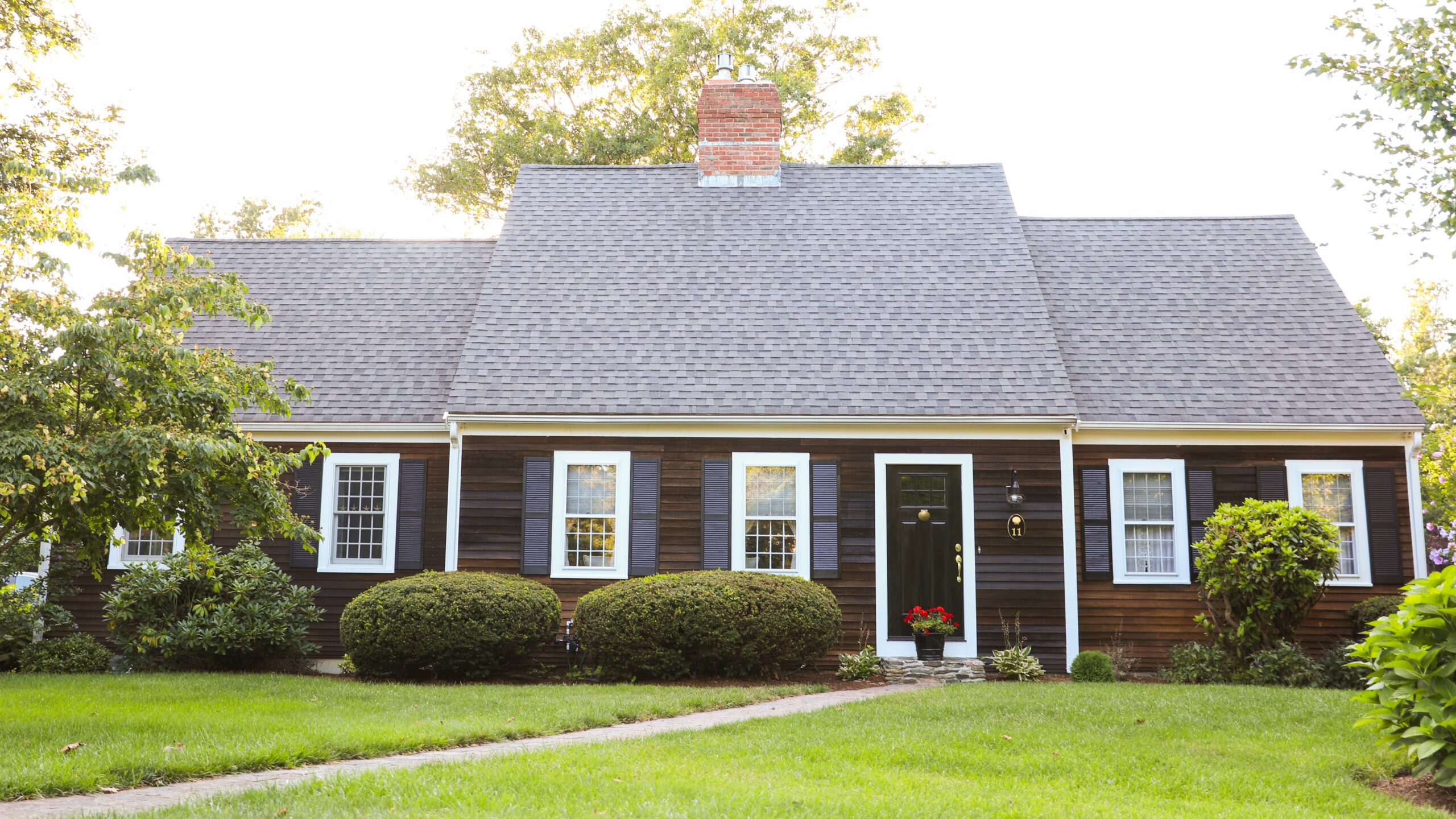 Home exterior with dark siding and a steep-sloped dark asphalt shingle roof.