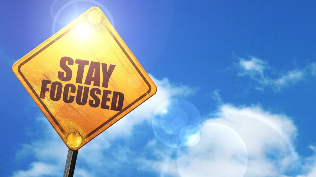 A road sign against a cloudy sky that reads, “Stay Focused.”