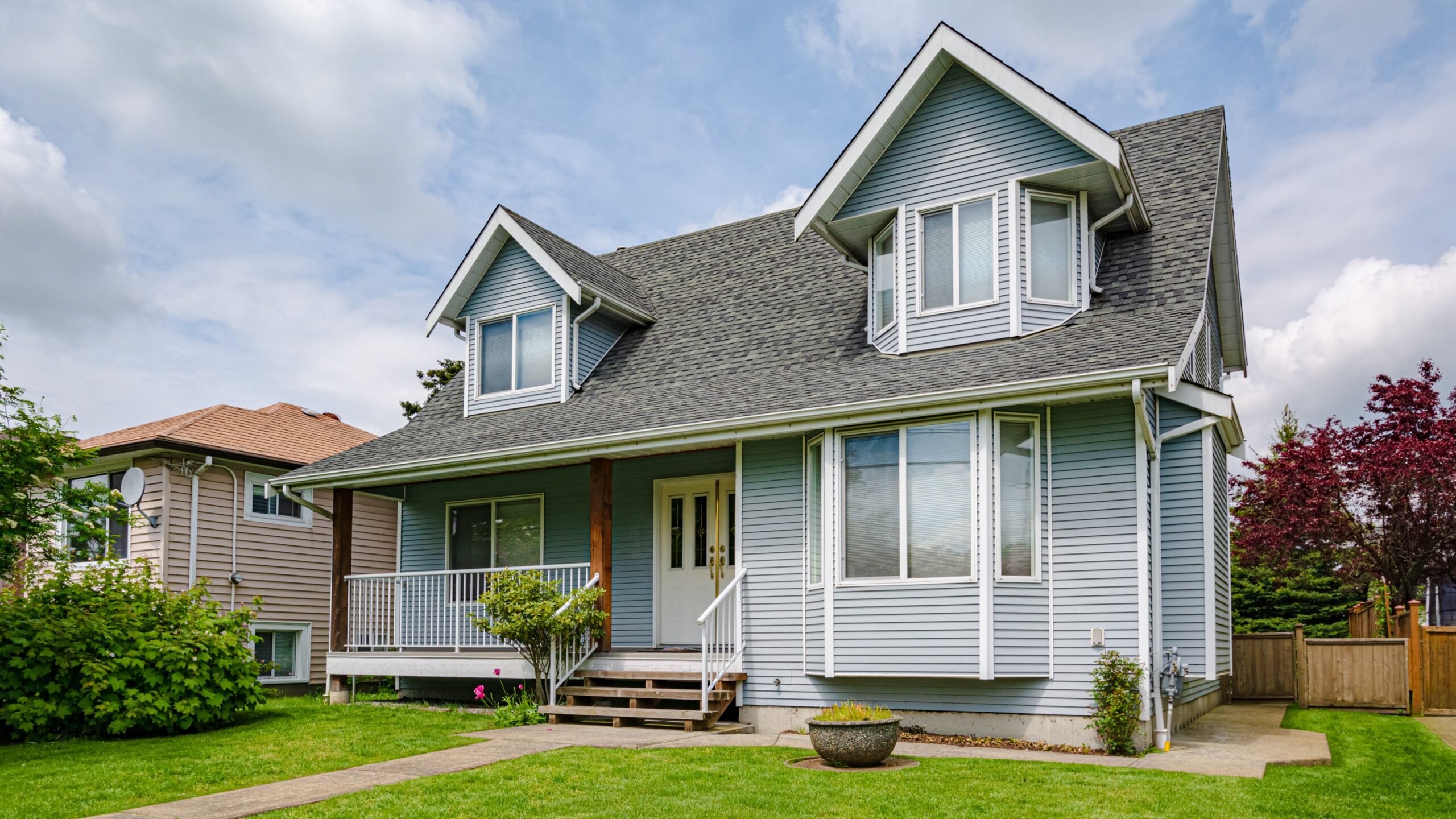 An Okmulgee, OK home with light blue vinyl siding, white trim, and a gray asphalt shingle roofing surrounded by a green lawn.