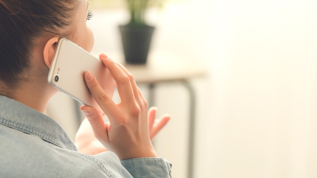 A close-up of a woman in her home talking on a cell phone